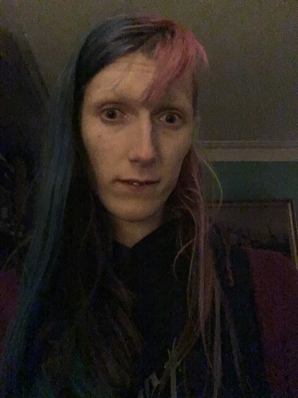 An image of a slightly wistful looking goth lady in low lighting